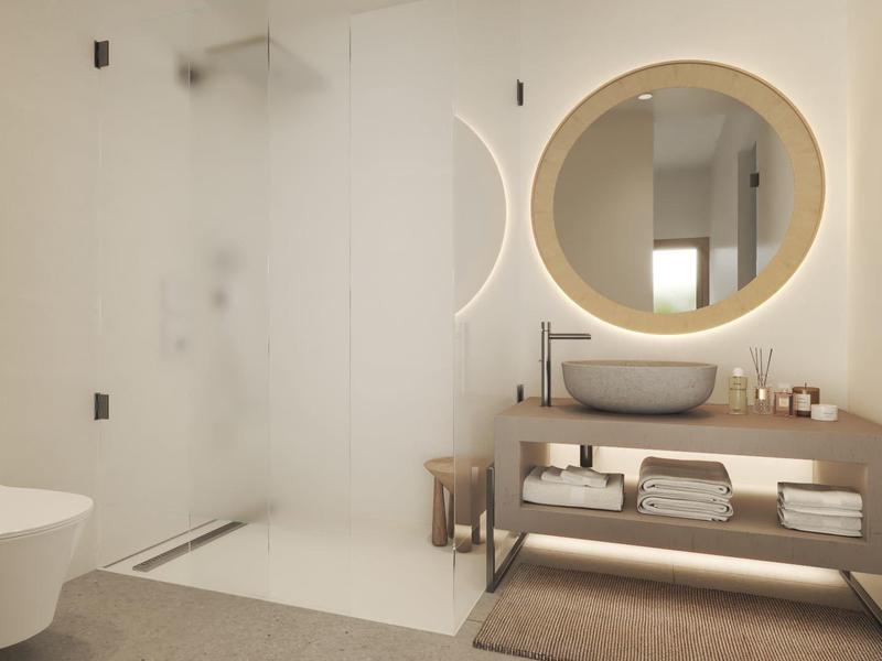 Moderne badkamer met inloopdouche, wandtoilet en verlichte ronde spiegel.