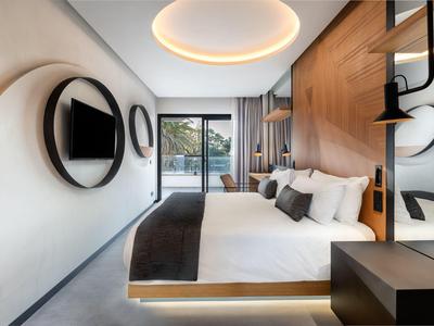Modernes Schlafzimmer mit rundem Deckenlicht, Holzdetails und Balkon mit Aussicht.