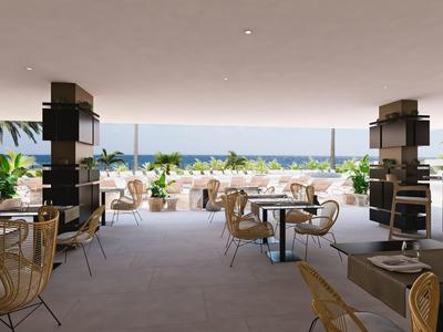 Moderner, offener Restaurantbereich mit Bambusstühlen, Tischen und Meerblick im Hintergrund.