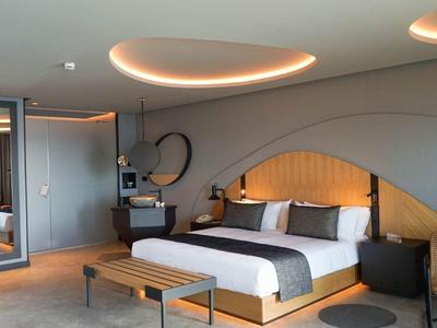 Modernes Hotelzimmer mit großem Bett, stilvollen runden Deckenleuchten und gemütlicher Sitzecke.
