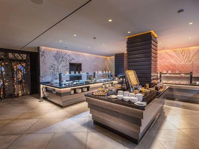 Moderner Hotelbuffetbereich mit Holztheken, heller Beleuchtung und dekorativen Wandmotiven.
