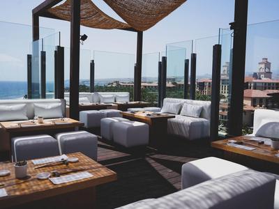 Moderner Außenbereich mit Holzmöbeln und Meerblick unter Sonnensegeln