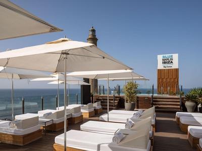 Lounge-Bereich mit weißen Liegen und Sonnenschirmen am Meer unter blauem Himmel