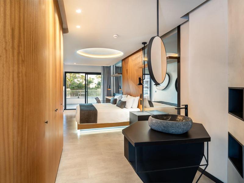 Habitación de hotel moderna con cama doble, revestimiento de madera y grandes ventanales.