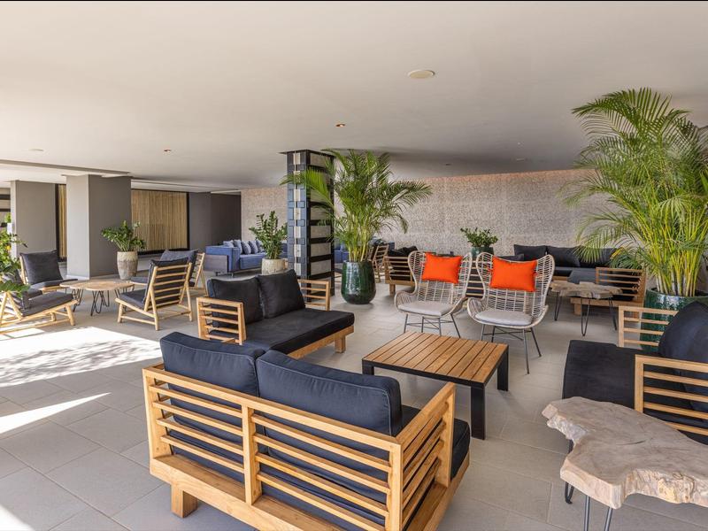 Amplia zona de descanso en hotel con muebles modernos de madera y plantas verdes para relajarse.