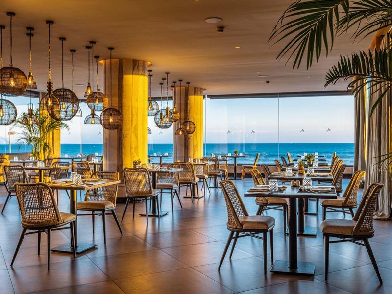 Restaurante con decoración moderna y vista al mar en un ambiente luminoso y espacioso.