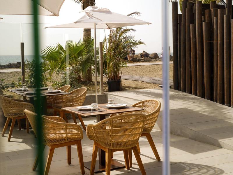 Cómodo mobiliario exterior con sillas de mimbre y sombrilla en terraza cerca del hotel.