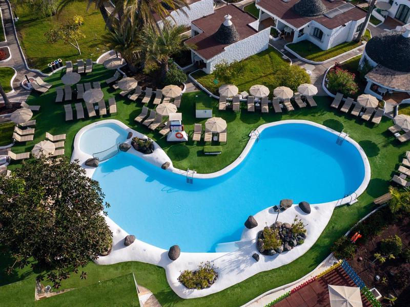 Aerial view of a kidney-shaped hotel pool surrounded by sunbeds and umbrellas.