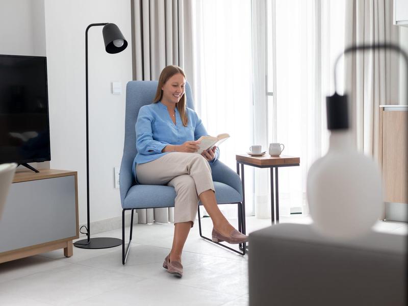 Una mujer se relaja en una silla en la sala moderna de un hotel con luz natural.