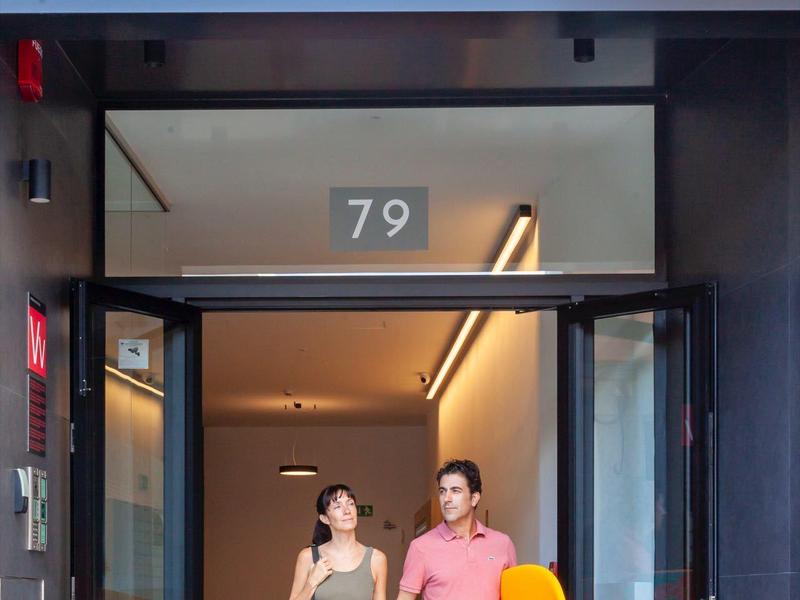 Dos jóvenes con equipo de surf están frente a la entrada de un hotel en Las Palmas.