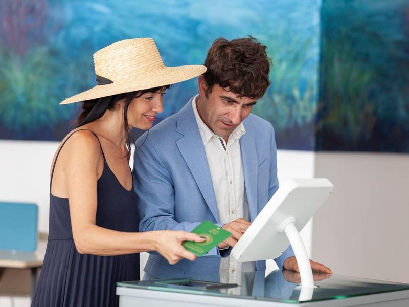 Pareja haciendo check-in en la recepción del hotel con pantalla de computadora.