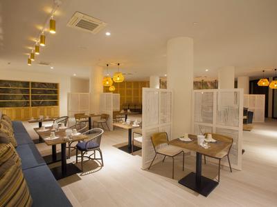 Modernes, helles Restaurant mit Holzmöbeln, bequemen Stühlen und indirekter Beleuchtung.