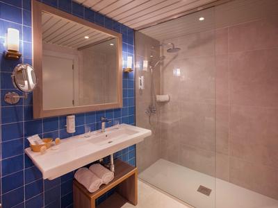 Modernes Badezimmer mit blau gekachelter Wand, großem Spiegel, Waschbecken und begehbarer Dusche.
