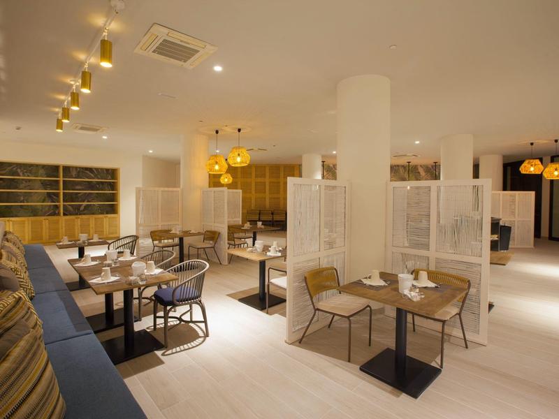 Modernes, helles Restaurant mit Holzmöbeln, bequemen Stühlen und indirekter Beleuchtung.