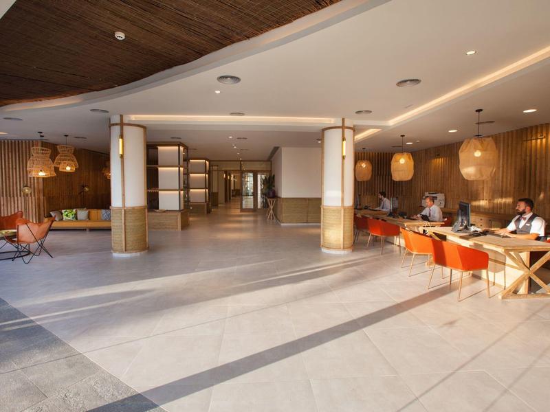 Heller Hotellobby mit Sitzbereichen, Holzwandverkleidung und weitläufigem Raum.