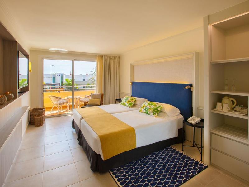 Modernes Hotelzimmer mit Doppelbett, Balkon und Stadtblick bei Tageslicht.