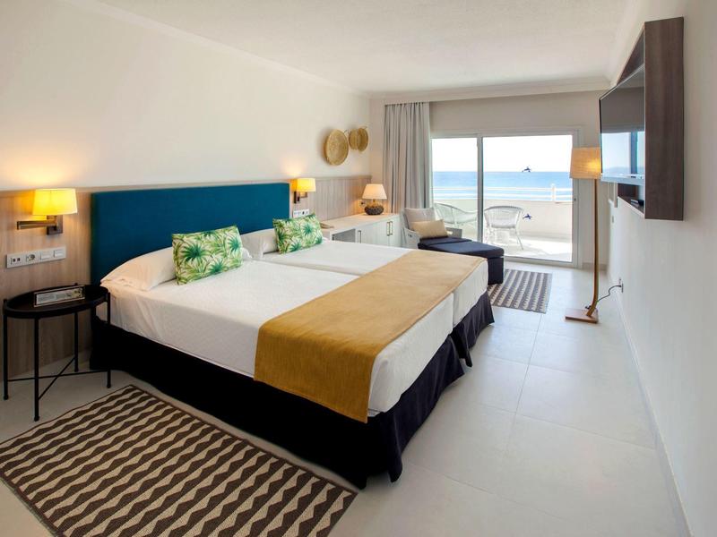 Modernes Hotelzimmer mit Doppelbett, Meerblick und hellem Interieur.