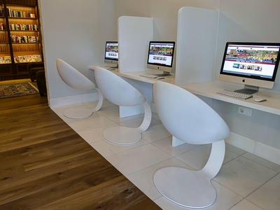 Moderne computerhoek met witte stoelen en Macs in een lichte kamer.