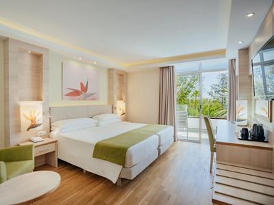 Jasny pokój hotelowy z dwoma łóżkami, balkonem i nowoczesnym designem.