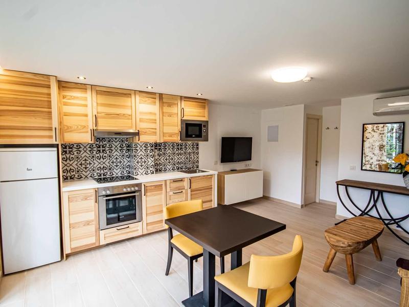 Nowoczesna kuchnia i jadalnia z drewnianymi meblami i wzorzystymi płytkami w pokoju hotelowym.