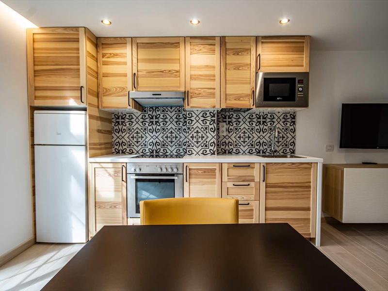Nowoczesna aneks kuchenny z drewnianymi szafkami i wzorzystymi kafelkami w hotelu.
