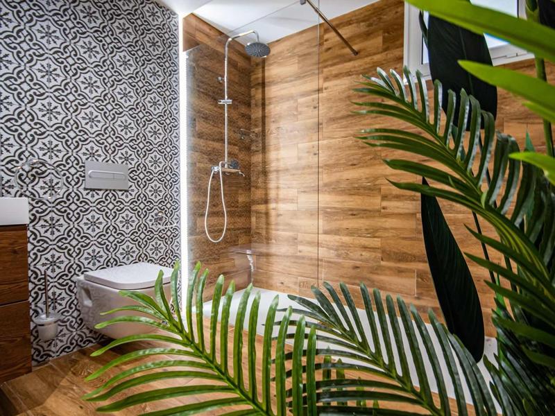 Nowoczesna łazienka z drewnianą okładziną, dekoracyjnymi kafelkami i zielonymi roślinami.