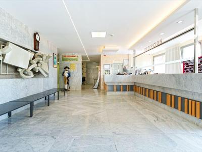 Nowoczesna lobby hotelowa z przestrzenną marmurową podłogą, ławką i jasnym recepcją.
