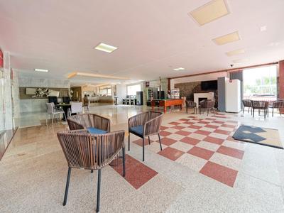 Hol hotelowy z miejscem do siedzenia, podłogą w szachownicę i dużymi oknami z widokiem na zewnątrz.