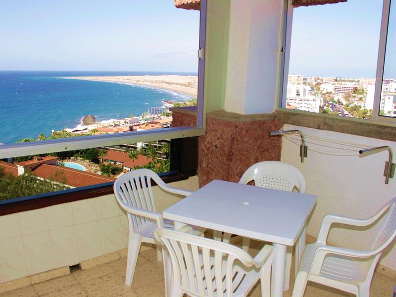 Balkon z białym plastikowym zestawem mebli i widokiem na morze pod czystym niebem.