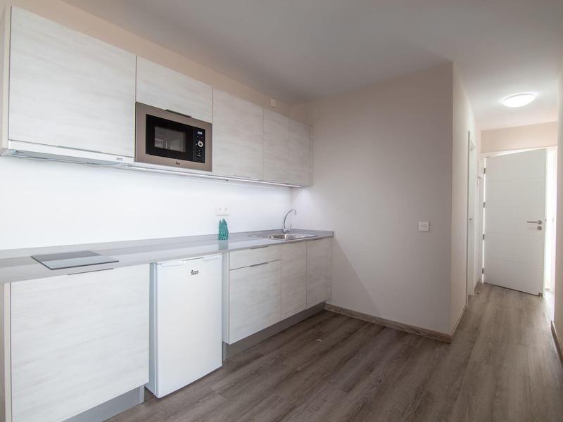 Jasny, nowoczesny aneks kuchenny z mikrofalówką i małą lodówką w pokoju hotelowym.