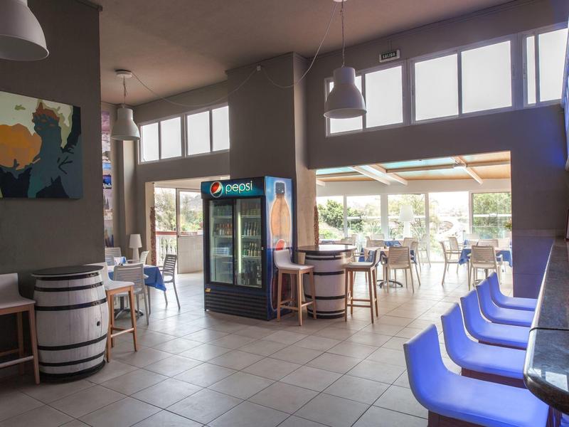 Jasna jadalnia z niebieskimi tapicerowanymi krzesłami i chłodzoną witryną w nowoczesnym barze hotelowym.