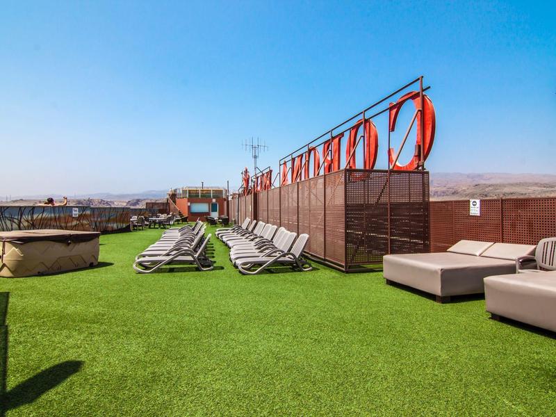 Taras na dachu z leżakami i trawnikiem pod błękitnym niebem