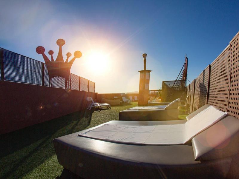 Zachód słońca nad leżakami obok placu zabaw z koroną i mieczem.