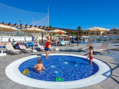 Des enfants jouent dans une piscine ronde pour enfants sous des parasols par temps clair à l'hôtel.