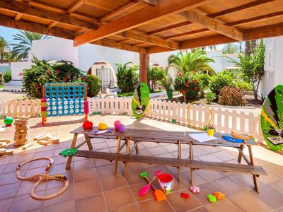 Espace extérieur couvert avec équipements de jeu et jouets, idéal pour les enfants en vacances.