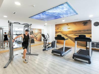 Moderner Fitnessraum mit Laufbändern, Trainingsgerät und Deckenprojektion eines Himmels.