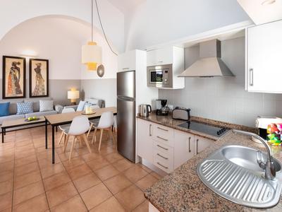 Moderní otevřená kuchyně s jídelním koutem a posezením v světlé místnosti s obloukovým stropem.