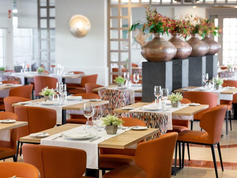 Restaurant élégant avec des chaises marron modernes et des tables dressées dans une ambiance lumineuse.