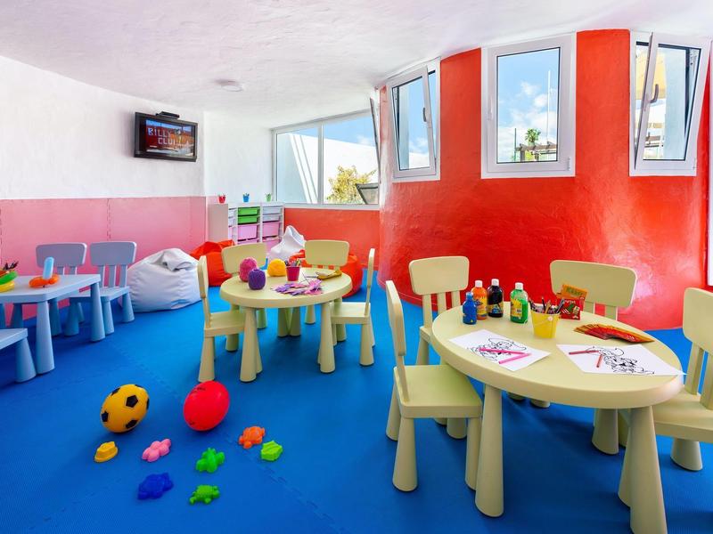 Salle de jeux colorée pour enfants avec tables, jouets et fenêtres dans un hôtel
