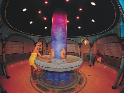 Großer, runder Springbrunnen mit bunter Säule in einem arktischen Innenraum mit Menschen.