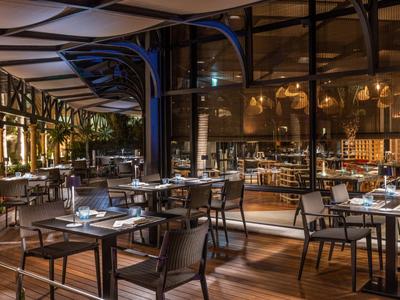 Elegantes Restaurant mit Holzboden, gedeckten Tischen und moderner Beleuchtung in warmen Farben.