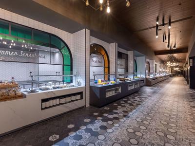 Großes, modernes Buffet mit beleuchteten Vitrinen und gemustertem Boden in warmem Licht.