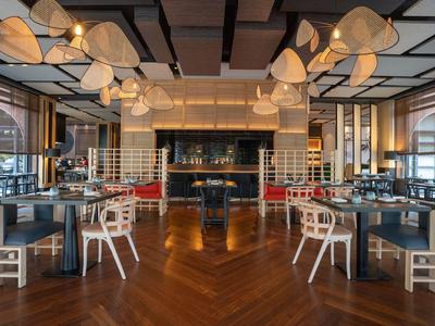 Restaurante elegante de hotel con suelos de madera, mesas de madera y sillas blancas.