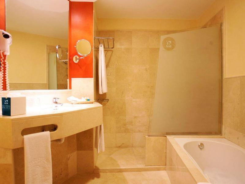 Hotelová koupelna s vanou, sprchou, umyvadlem a velkým zrcadlem