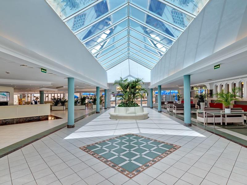 Lobby d'hôtel moderne et lumineuse avec toit en verre et espaces de repos à gauche et à droite