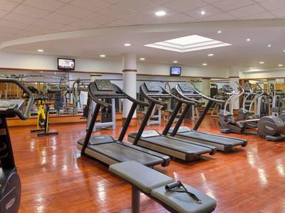 Interiér dobře vybavené posilovny s běžeckými pásy a závažími.