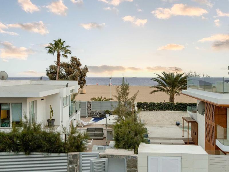 Nowoczesne małe domy z widokiem na morze, palmami i pochmurnym niebem.