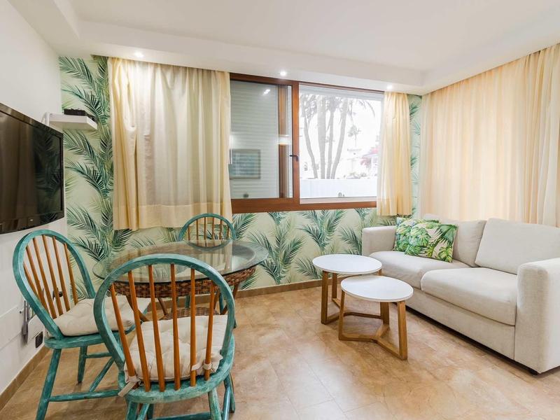 Nowoczesny salon z sofą, telewizorem, stołem i kolorowymi krzesłami w pokoju hotelowym.