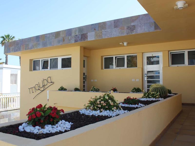 Wejście do hotelu z klombem i żółtymi ścianami pod czystym niebem.