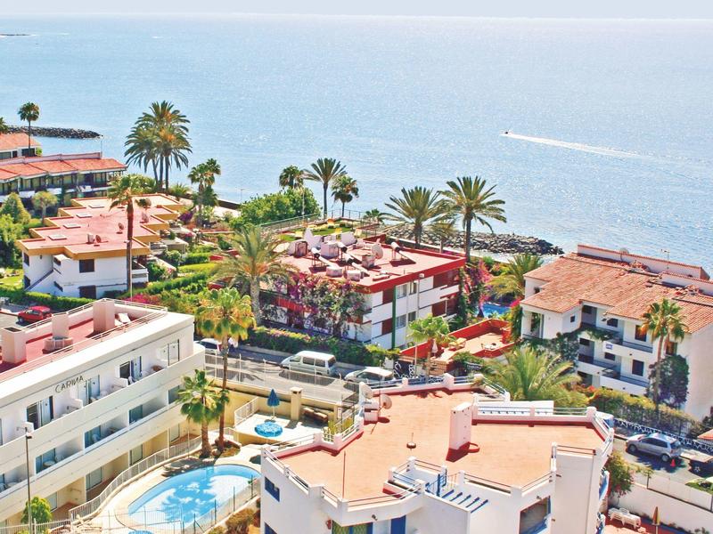 Nowoczesny salon z beżową sofą, niebieską zasłoną w wzory i drewnianymi meblami.